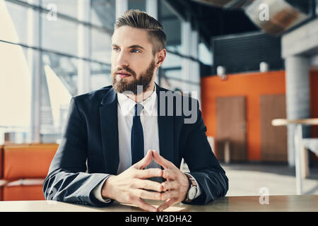 Pensive businessman looking away assis à un bureau moderne Banque D'Images