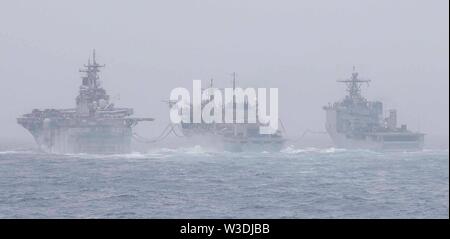 190714-N-MT581-0023 en mer d'Oman (14 juillet 2019) navire d'assaut amphibie USS Boxer (DG 4), à gauche, et navire de débarquement amphibie dock USS Harpers Ferry (LSD 49), extrême droite, effectuer une opération de ravitaillement en mer avec le soutien de combat l'évolution rapide navire USNS arctique (T-AOE 8). Boxer et Harpers Ferry font partie du groupe amphibie Boxer et la 11e unité expéditionnaire maritime et de l'équipe sont affectés à la 5e Flotte Secteur d'opérations à l'appui des opérations navales pour assurer la stabilité et la sécurité maritime dans la région Centrale, reliant la Méditerranée et le Pacifique par la Western Indian Ocea Banque D'Images