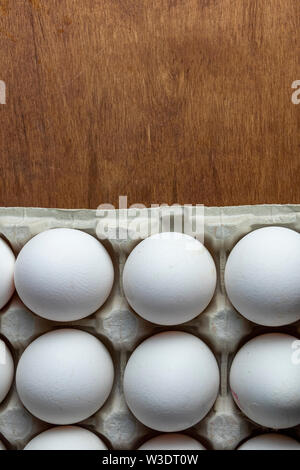 Les oeufs de poule sont les matières dans le bac. La coquille est blanc dans les œufs. Dans une section est une coquille de l'oeuf. Sur un œuf se trouve une plume de couleur blanche. Background en bois Banque D'Images