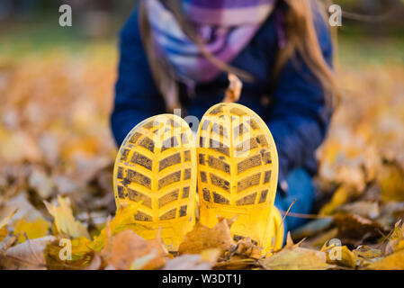 Preteen girl s'asseoir à l'automne dans le parc chaussures de pluie Banque D'Images