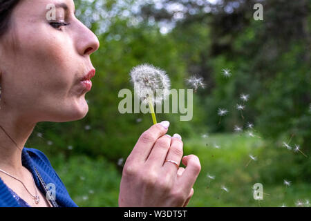 Happy woman blowing dandelion sur fond de ciel, s'amuser et jouer en plein air, teen girl profiter de la nature, les vacances d'été et les jours fériés, Banque D'Images