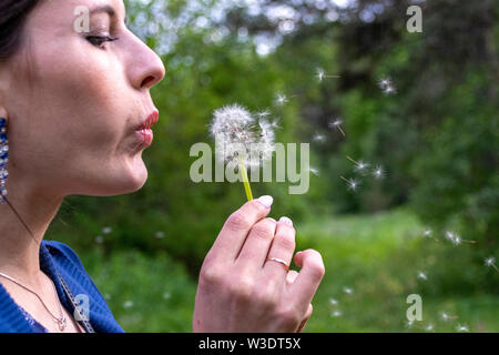 Happy woman blowing dandelion sur fond de ciel, s'amuser et jouer en plein air, teen girl profiter de la nature, les vacances d'été et les jours fériés, Banque D'Images