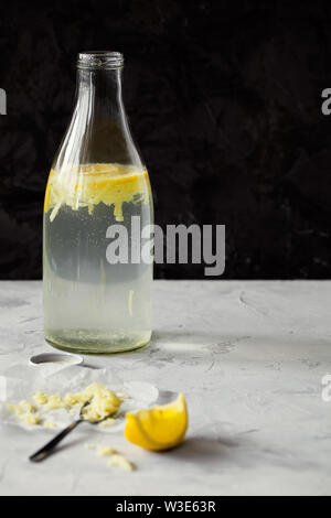 Rafraîchissant de l'eau infusée Maison de désintoxication ou de la limonade dans des bouteilles en verre avec le gingembre râpé et de citron sur fond sombre close-up avec copie espace pour le texte Banque D'Images