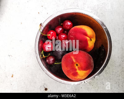 L'été frais mûrs de petits fruits et de fruits, pêches, abricots, cerises et fraises dans une plaque ronde Banque D'Images