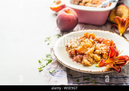 Close up of delicious peach cobbler dessert en plaque sur fond clair avec la casserole et pêches fraîches . Copy space Banque D'Images