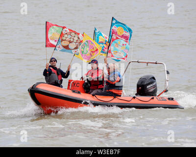 Sheerness, Kent, UK. 15 juillet, 2019. T100 Walking Festival est organisé par arts group Kinetika, qui comprend une série de 15 jours de marche sur les deux côtés de l'estuaire de la Tamise. Aujourd'hui, les organisateurs et les participants ont traversé l'estuaire de la Tamise avec l'aide de l'estuaire de Thames Yacht Club (Essex) dans deux de leurs bateaux et d'atterrir à l'île de Sheppey du Club de Voile cale à Sheerness, Kent, pour rencontrer d'autres marcheurs qui prennent part à la marche d'aujourd'hui de Sheerness de Minster sur mer. Credit : James Bell/Alamy Live News Banque D'Images