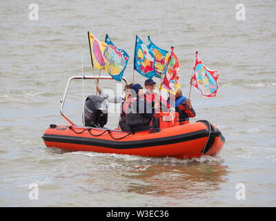 Sheerness, Kent, UK. 15 juillet, 2019. T100 Walking Festival est organisé par arts group Kinetika, qui comprend une série de 15 jours de marche sur les deux côtés de l'estuaire de la Tamise. Aujourd'hui, les organisateurs et les participants ont traversé l'estuaire de la Tamise avec l'aide de l'estuaire de Thames Yacht Club (Essex) dans deux de leurs bateaux et d'atterrir à l'île de Sheppey du Club de Voile cale à Sheerness, Kent, pour rencontrer d'autres marcheurs qui prennent part à la marche d'aujourd'hui de Sheerness de Minster sur mer. Credit : James Bell/Alamy Live News Banque D'Images