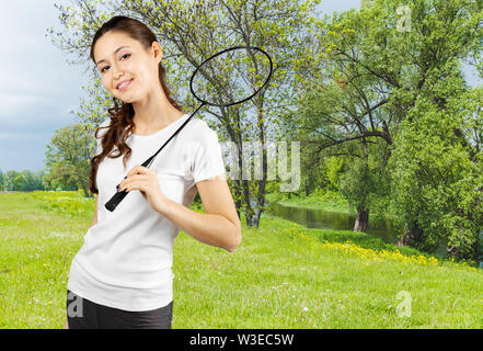 Jolie jeune femme à jouer au badminton dans un parc de la ville sur une belle journée d'été Banque D'Images