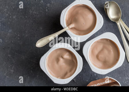 Yogourt Yogourt aromatisé au chocolat sur fond gris foncé avec cuillères - top voir photo Banque D'Images