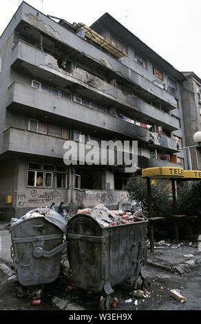 5 avril 1993 pendant le siège de Sarajevo : deux jeunes filles passent devant un immeuble très endommagés dans Slobodana principa (rebaptisé Kulovica après la guerre) dans le centre-ville. Banque D'Images