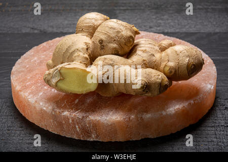 Les racines de gingembre frais sel rose de Perse sur board close up sur fond de bois noir, concept alimentaire asiatique Banque D'Images