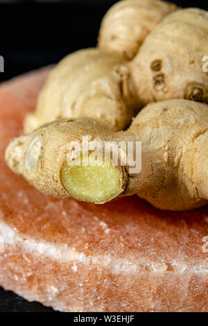 Les racines de gingembre frais sel rose de Perse sur board close up sur fond de bois noir, concept alimentaire asiatique Banque D'Images