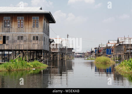 Haspres Thauk, Myanmar - Avril 2019 : Birman traditionnel maison flottante reflétant dans l'eau du lac Inle. Banque D'Images