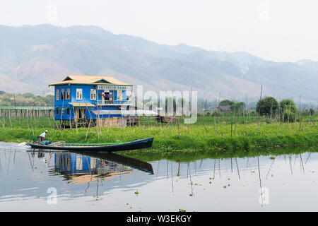 Haspres Thauk, Myanmar - Avril 2019 : Birman traditionnel maison flottante reflétant dans l'eau du lac Inle. Banque D'Images