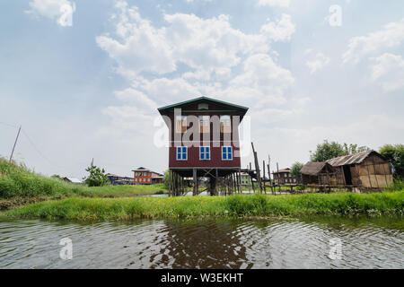 Haspres Thauk, Myanmar - Avril 2019 : Birman traditionnel maison flottante reflétant dans l'eau du lac Inle. Banque D'Images