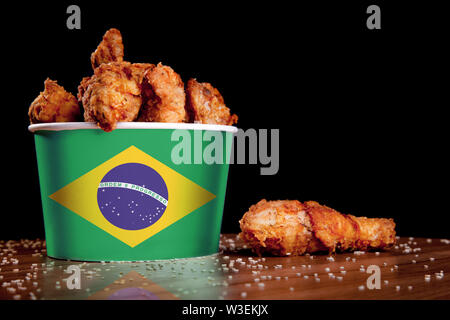 Cuisses de poulet BBQ dans la benne d'un drapeau du Brésil sur une table en bois et fond noir. Banque D'Images