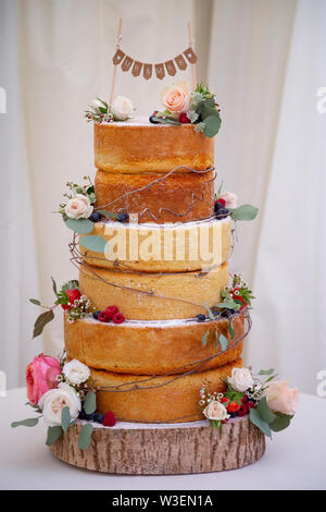 Une éponge Victoria à trois niveaux, gâteau de mariage décoré de feuilles d'eucalyptus, de roses et de fruits Banque D'Images