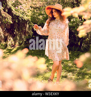 Belle jeune femme dansant dans le parc. Hat et de tenue d'été. L'humeur de l'été. Banque D'Images