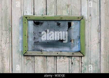 Ancien trou dans la grille sur l'ancienne fenêtre en bois Banque D'Images