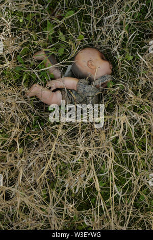 Old weathered poupée sur l'herbe. Broken toy spooky dans les bois. Banque D'Images