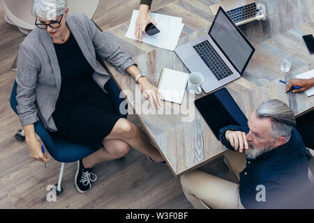 Vue de dessus d'hommes d'affaires assis à table looking at présentation. L'équipe d'attention à la présentation. Banque D'Images