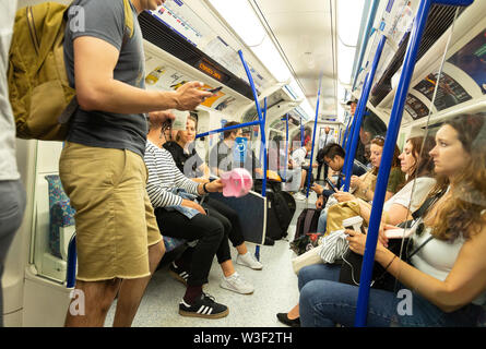 Métro de Londres ; téléphone mobile un passager utilisant un téléphone cellulaire dans un tube train plein de gens, Londres UK Banque D'Images