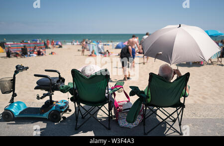 Mobilité couple profiter du soleil sur la plage de Sandbanks Poole Banque D'Images