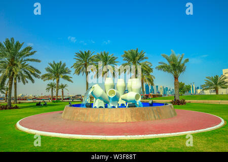 Doha, Qatar - 16 Février 2019 : des pots d'eau ou fontaine fontaine jar et pal d'arbres sur la promenade de la Corniche et le port de Dhow avec l'entreprise lointain Banque D'Images