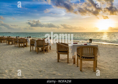 Le restaurant tropical sur la plage de sable. Paysage du magnifique coucher de soleil aux Maldives Île avec ciel coloré et dramatique nuages sur la mer ondulée. Banque D'Images