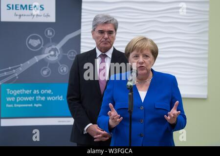 15 juillet 2019, Saxe, Görlitz : membre du conseil d'administration de Siemens Joe Kaeser et la Chancelière Angela Merkel (CDU) se tiennent l'un derrière l'autre au cours d'une conférence de presse. Un mois et demi avant l'élections de l'état de Saxe, Merkel visite l'usine Siemens à la Neisse ville de Görlitz et une réunion du réseau de femmes dans la capitale de l'état. Photo : Sebastian Kahnert/dpa-Zentralbild/dpa Banque D'Images