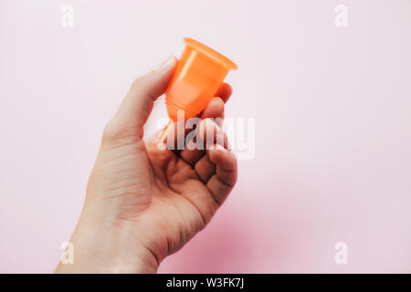 Woman's hand holding coupelle menstruelle sur fond rose. Banque D'Images