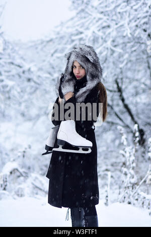 Fille avec paire de patins à arbres dans la neige Banque D'Images