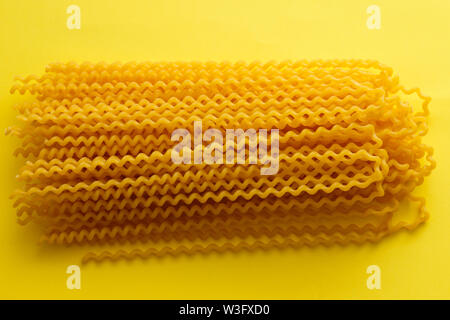 Fusilli lunghi brut pâtes sur fond jaune.jpg Banque D'Images