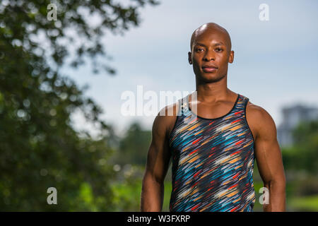 Portrait d'un athletic homme noir avec chemise de couleur abstraite qui pose à l'extérieur dans un parc Banque D'Images