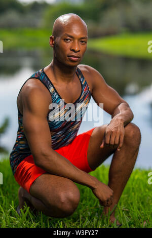 Portrait d'un beau jeune homme accroupi dans un post. Modèle masculin portant des vêtements de sport dans le parc Banque D'Images