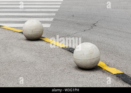 Deux boules de béton comme une frontière entre le trottoir et la route. Banque D'Images