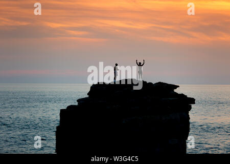 Portland Bill, Dorset, UK. 15 juillet, 2019. Deux personnes admirer le coucher de soleil depuis le haut de Pulpit Rock sur Portland Bill, Dorset, après une journée sans nuages sur la côte sud-ouest de la Grande-Bretagne. Peter Lopeman/Alamy Live News Banque D'Images