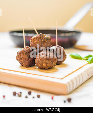 Les boulettes de viande sur une planche en bois avec des cure-dents contre fond blanc Banque D'Images