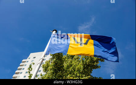 La Barbade drapeau. Symbole national en agitant sur perche haut bâtiment, et fond de ciel bleu clair, journée ensoleillée. Indepedence day concept. Banque D'Images