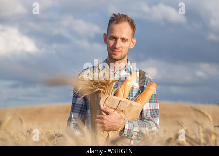 Agriculteur ou baker avec baguettes de seigle, champ de blé. Banque D'Images