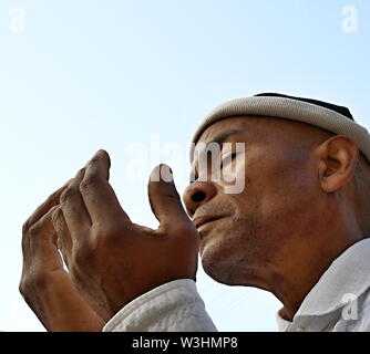 Homme noir à prier Dieu avec les bras tendus à la recherche jusqu'au ciel bleu Caraïbes homme priant et stock image stock photo Banque D'Images