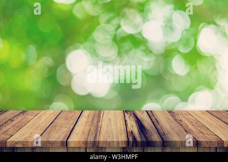 Table en bois vide et abstrait vert feuilles floue flou d'arrière-plan de la texture, de montage d'affichage avec l'exemplaire de l'espace. Banque D'Images