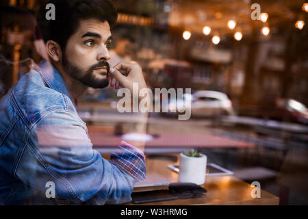 Jeune homme pensant par la fenêtre bar Banque D'Images