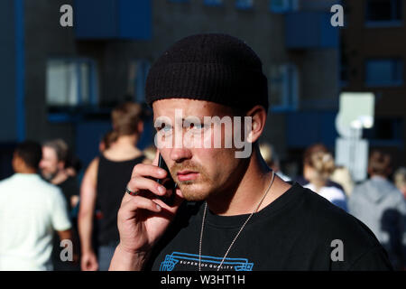 Man wearing knit cap parlant au téléphone dans la rue au cours de Kallio Block Party 2017 à Helsinki, Finlande Banque D'Images