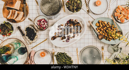 Famille, amis dîner de collecte. Télévision à jeter de l'épaule d'agneau rôti, salades, légumes cuits, des collations, du pain, la limonade en verseuse et son mimosa en fleurs Banque D'Images