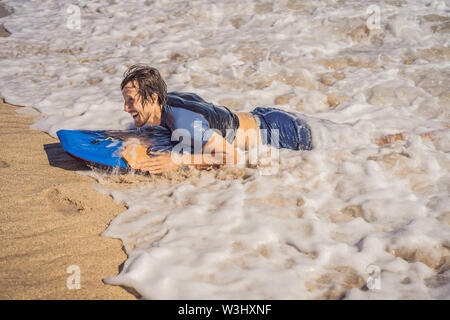 Jeune homme à la planche de surf à la plage Banque D'Images