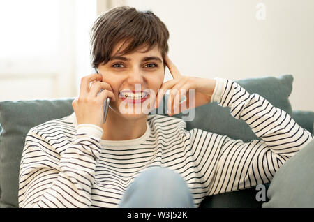 Happy young woman on smart mobile phone chat dans les applications de médias sociaux assis sur le canapé à la maison dans les gens et le mode de vie sociale, lance une Banque D'Images