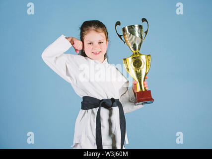 Je suis le meilleur coup de l'énergie.. et l'activité pour les enfants. pratiquer le Kung Fu. enfance heureuse. sport succès en combat singulier. girl avec champion cup. arts martiaux. gagnant petite fille dans gi sportswear. Banque D'Images