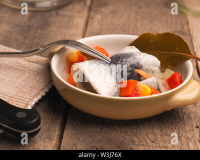 Délicieux rollmops dans un bol en céramique sur une table de cuisine en bois Banque D'Images