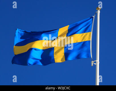 De brandir le drapeau de la suède avec le ciel bleu sur l'arrière-plan Banque D'Images